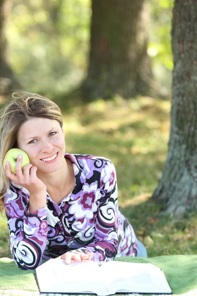 Mujer joven comiendo una manzana y leyendo un libro la Biblia —  Fotos de Stock