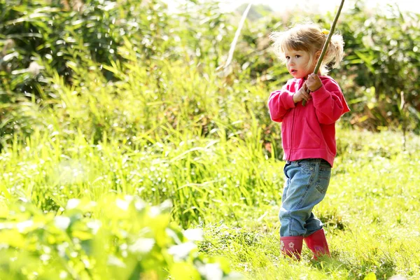 Beautiful little girl outdoors near a lake in rubber boots — Stock Photo, Image