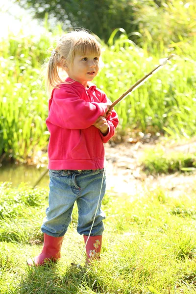 Vacker liten flicka i gummi stövlar på sjön — Stockfoto