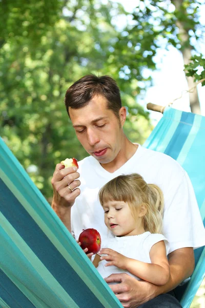 Little girl eats an apple with dad — Stock Photo, Image