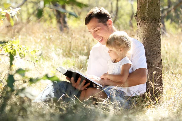 Giovane padre con sua figlia legge la Bibbia — Foto Stock