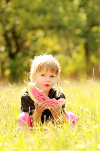 Ein schönes kleines Mädchen isst Wassermelone in der Natur — Stockfoto