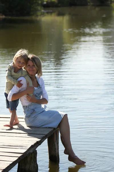 Little girl with her mother near lake on nature — Stock Photo, Image