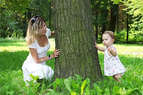 Menina bonita com mãe perto de árvore na natureza — Fotografia de Stock