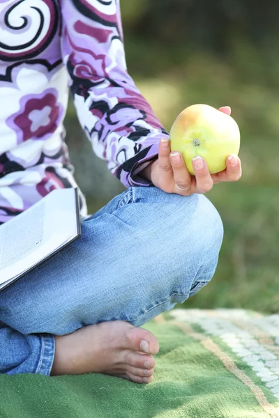 Mujer joven comiendo una manzana y leyendo un libro la Biblia —  Fotos de Stock