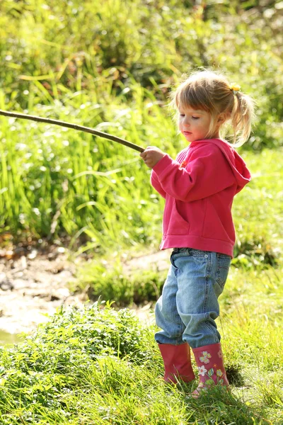 Vacker liten flicka utomhus nära en sjö i gummistövlar — Stockfoto