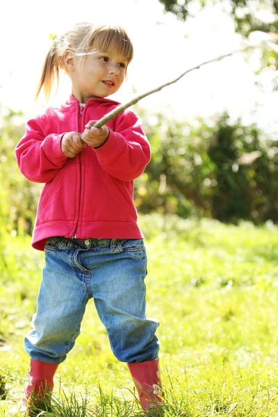 Beautiful little girl outdoors near a lake in rubber boots — Stock Photo, Image