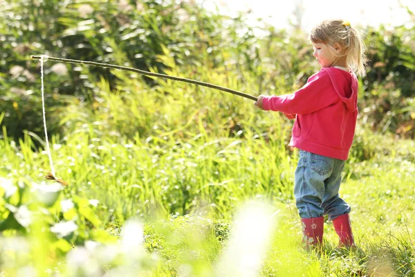 Beautiful little girl outdoors near a lake in rubber boots — Stock Photo, Image