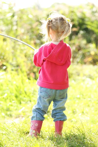 Vacker liten flicka utomhus nära en sjö i gummistövlar — Stockfoto