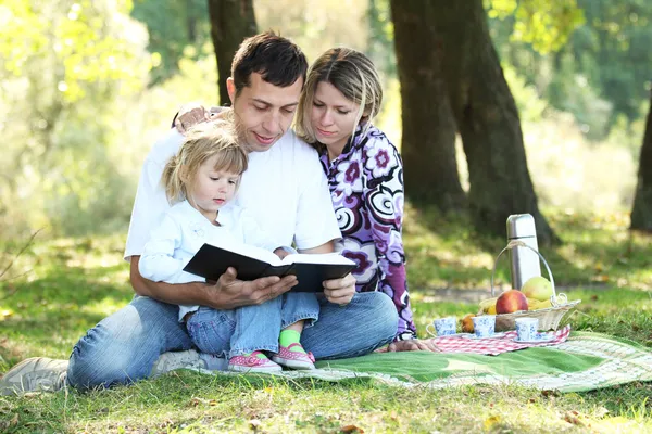 Jonge gezin met een kind lezen van de Bijbel — Stockfoto