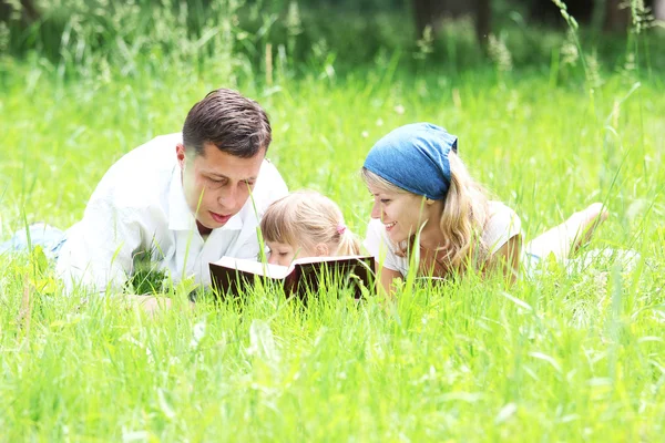 Jeune famille avec un enfant lisant la Bible — Photo