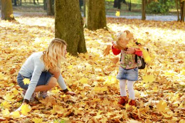 güzel küçük bir kız annesi sonbahar orman ile oynamak