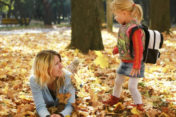Vacker liten flicka spelar med sin mor i skogen höst — Stockfoto