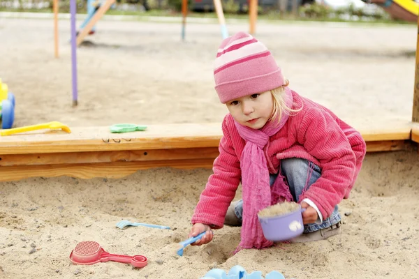 Vacker liten flicka i en sandlåda i naturen — Stockfoto