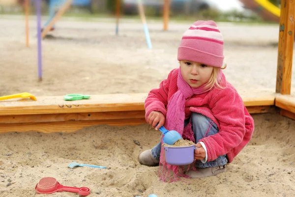 Vacker liten flicka i en sandlåda i naturen — Stockfoto