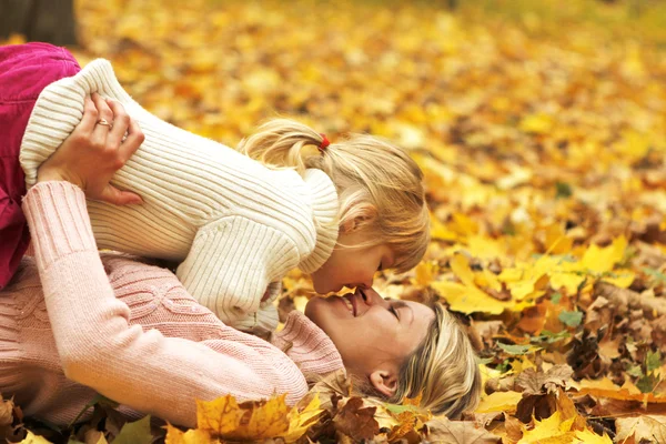 Vacker liten flicka spelar med sin mor i skogen höst — Stockfoto