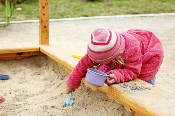 Vacker liten flicka i en sandlåda i naturen — Stockfoto