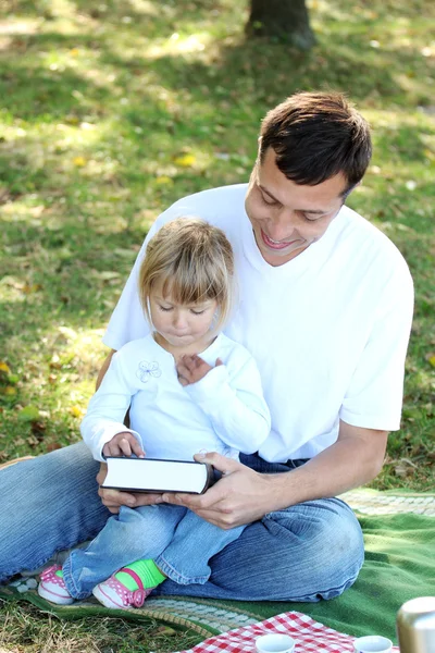 Padre joven con una hija joven leer la Biblia en la naturaleza — Foto de Stock