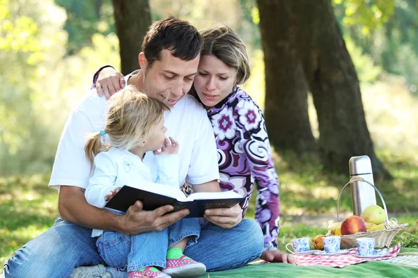 Familia joven leer la Biblia en la naturaleza —  Fotos de Stock