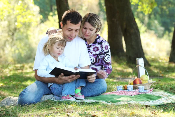 Familia joven leer la Biblia en la naturaleza —  Fotos de Stock