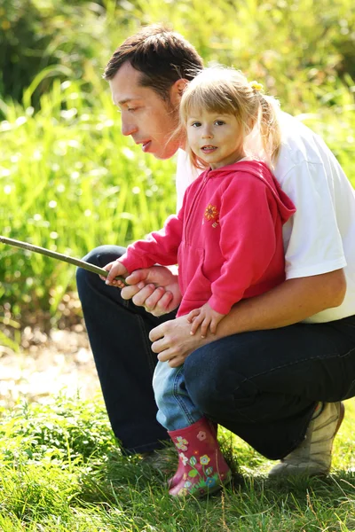 Far med en liten dotter vid sjön i gummi stövlar — Stockfoto