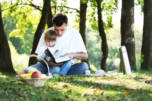 Giovane padre con una giovane figlia leggere la Bibbia in natura — Foto Stock