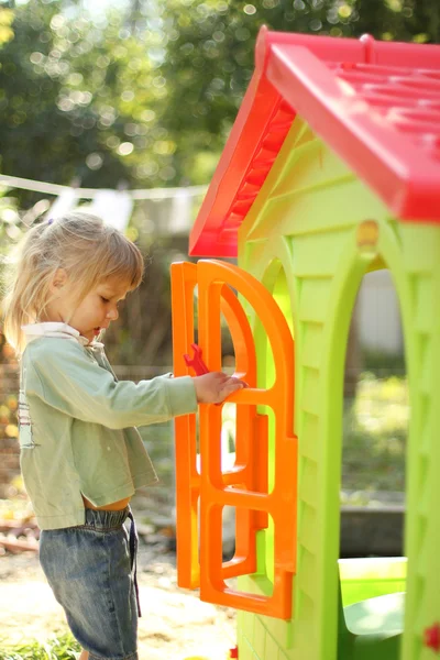 Little girl with a children's playhouse — Stock Photo, Image