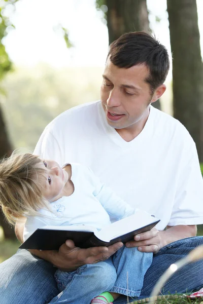 Padre con una hija joven leer la Biblia en la naturaleza — Foto de Stock