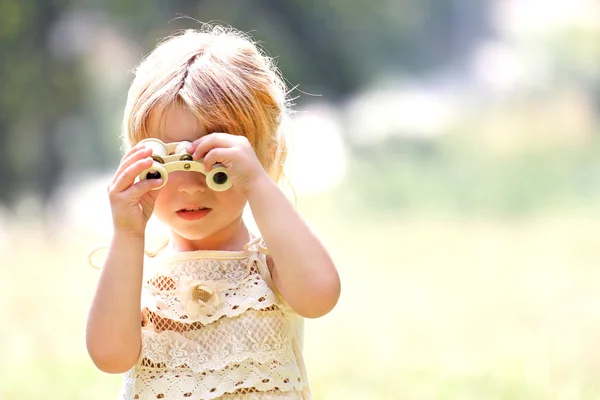 Beautiful young girl on nature with binoculars — Stock Photo, Image