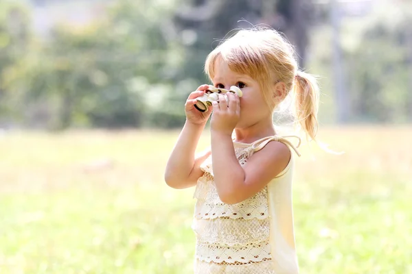 Beautiful young girl on nature with binoculars — Stock Photo, Image