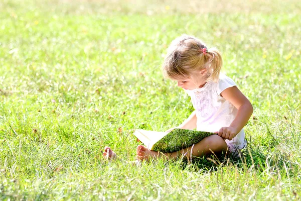 Vacker liten flicka i naturen med bok — Stockfoto