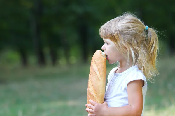 Bella bambina nella natura con un panino — Foto Stock