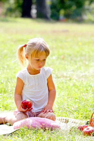 Красивая маленькая девочка на улице с яблоком — стоковое фото