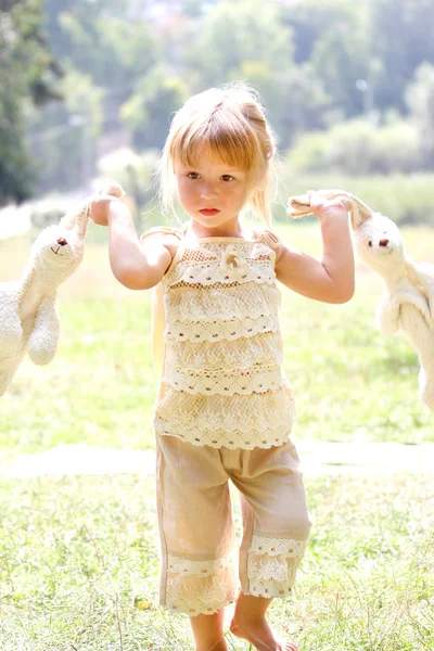 Beautiful little girl in nature with rabbits — Stock Photo, Image