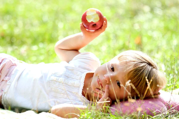 Vacker liten flicka utomhus med äpple — Stockfoto