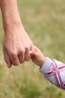 Ebeveyn küçük bir çocuğun elini tutuyor.