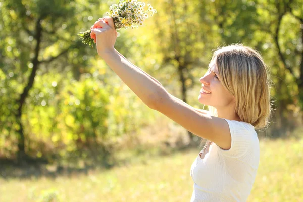 Mujer joven en la naturaleza con un ramo de flores —  Fotos de Stock