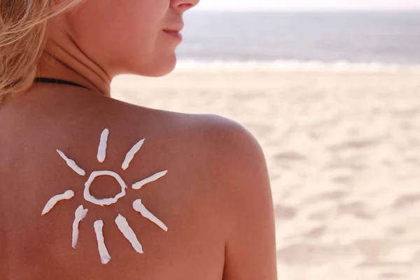 Sun cream på kvinnliga baksidan på stranden — Stockfoto