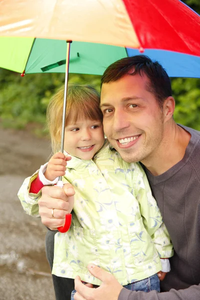 Chica con un paraguas en la lluvia con su padre —  Fotos de Stock