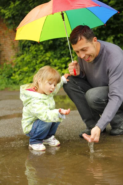 Dziewczyna z parasol w deszczu z ojcem — Zdjęcie stockowe