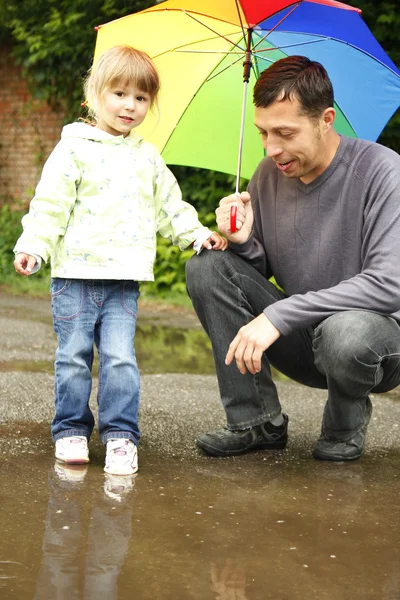 Chica con un paraguas en la lluvia con su padre —  Fotos de Stock