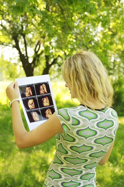 Pregnant girl on nature with ultrasound photos — Stock Photo, Image