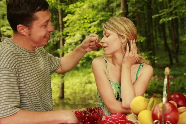 A couple in love at a picnic with cherries — Stock Photo, Image