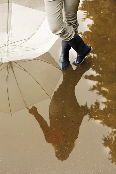 一男子用一把雨伞在他的靴子和水坑 — 图库照片