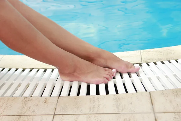Vrouwelijke benen in het zwembad water — Stockfoto