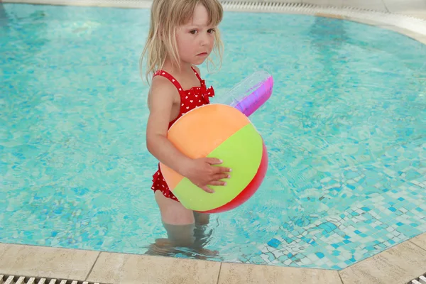 Klein meisje in het zwembad water met een bal — Stockfoto