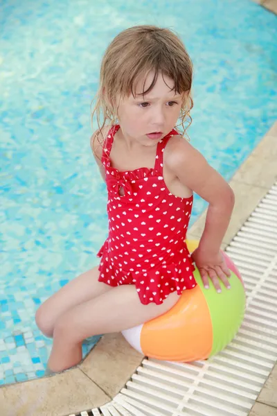 Klein meisje in het zwembad water met een bal — Stockfoto