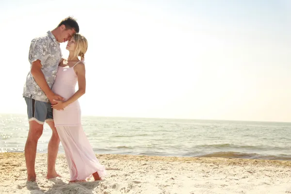 Gravida par i kärlek på stranden — Stockfoto