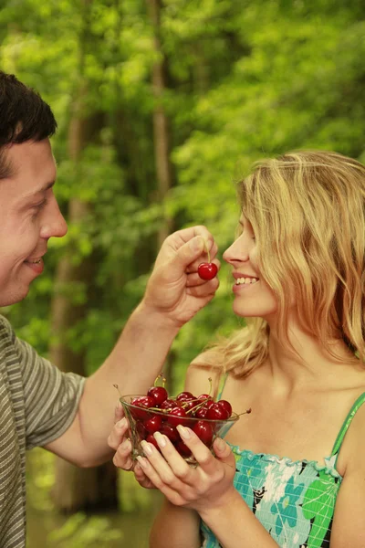 Ett par i kärlek på en picknick med körsbär — Stockfoto