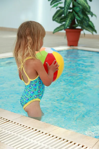 Klein meisje in het zwembad water met een bal — Stockfoto